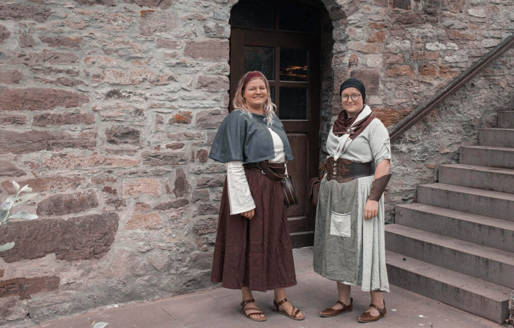 Zwei Frauen in mittelalterlichen Gewändern vor der Bauernburg in Ottenhausen. Escape Room Ottenhausen